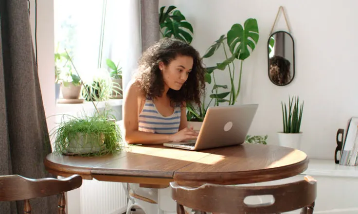 woman using computer surrounded by plants