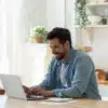 man using a computer in his kitchen.