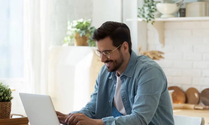 man using a computer in his kitchen.