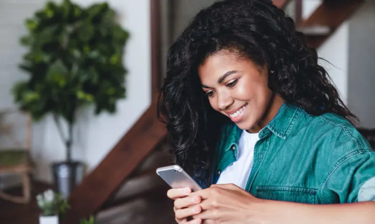 person sitting on couch smiling at phone