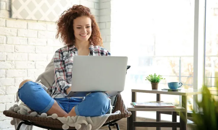 person sitting in a chair smiling at computer