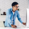 man standing up using a desktop computer