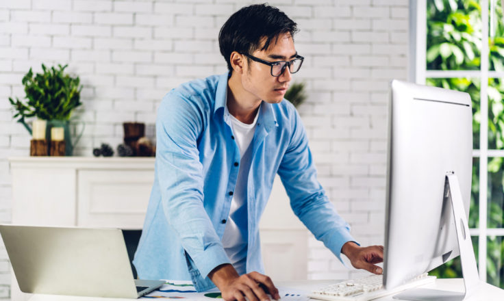 man standing up using a desktop computer