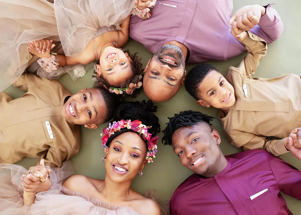 tq with her family laying on the ground  in a circle holding hands, smiling up at the camera