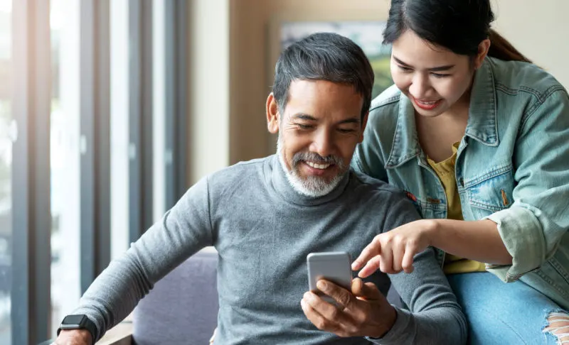 woman pointing to phone man is holding while sitting down