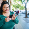 woman using phone on the sidewalk