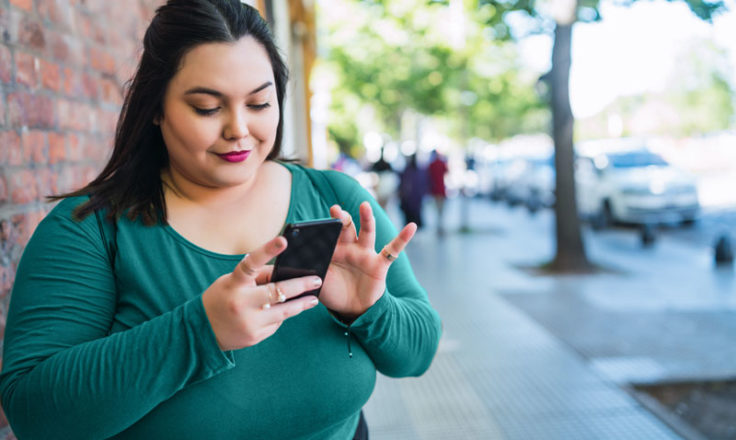 woman using phone on the sidewalk