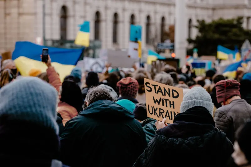 crowd holding flags and signs in support of ukraine