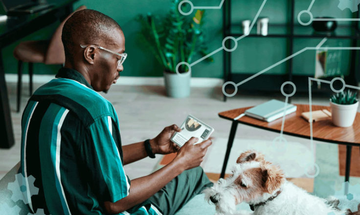 person using an ipad sitting on the couch next to their dog