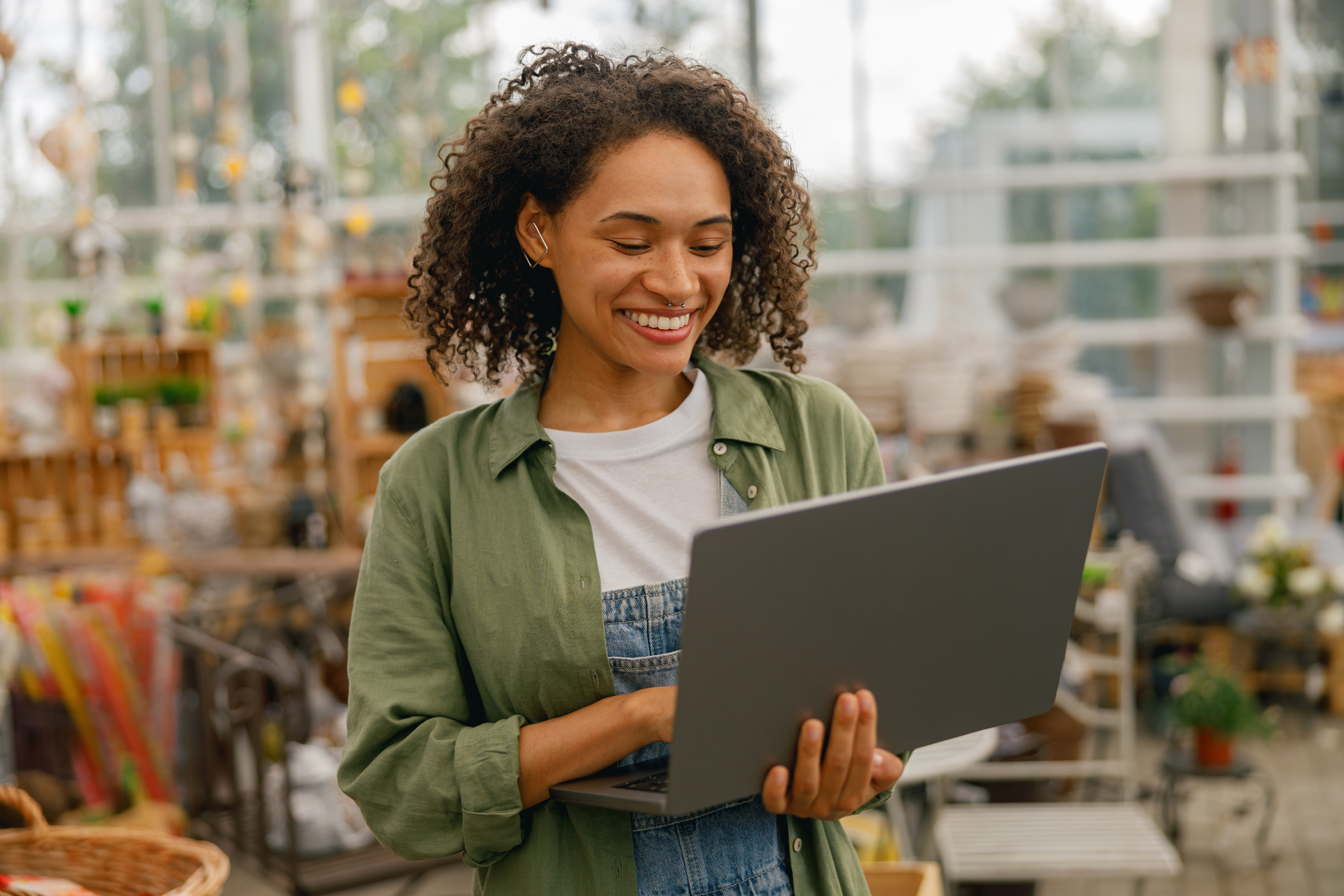 Female gardening shop owner working on laptop on garden store background. High quality photo